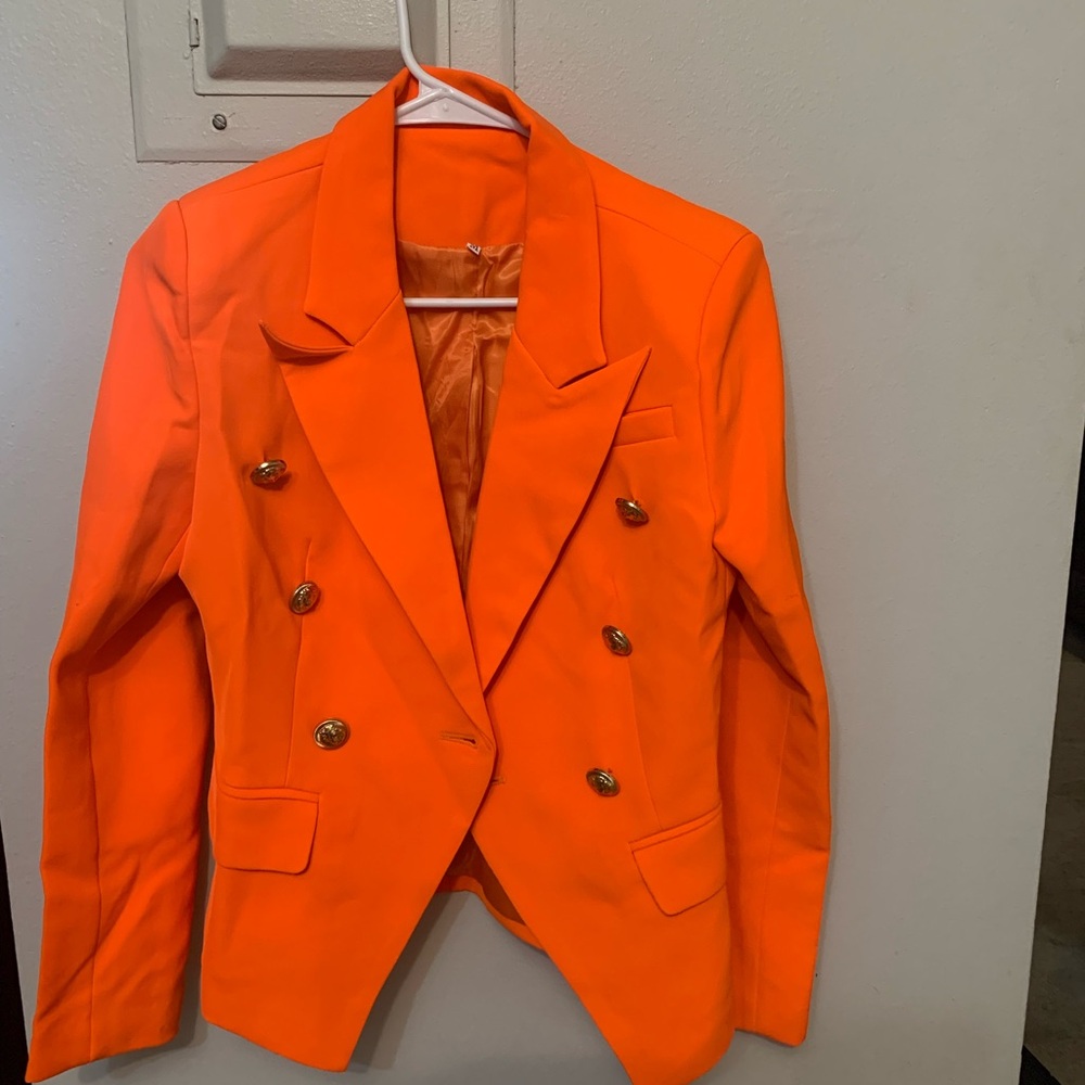 Vibrant orange blazer with gold buttons in front as well as sleeves